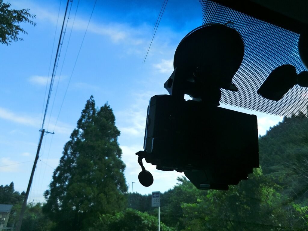 Compact camera held to a car windscreen by a suction-cup mount, seen from inside the cabin