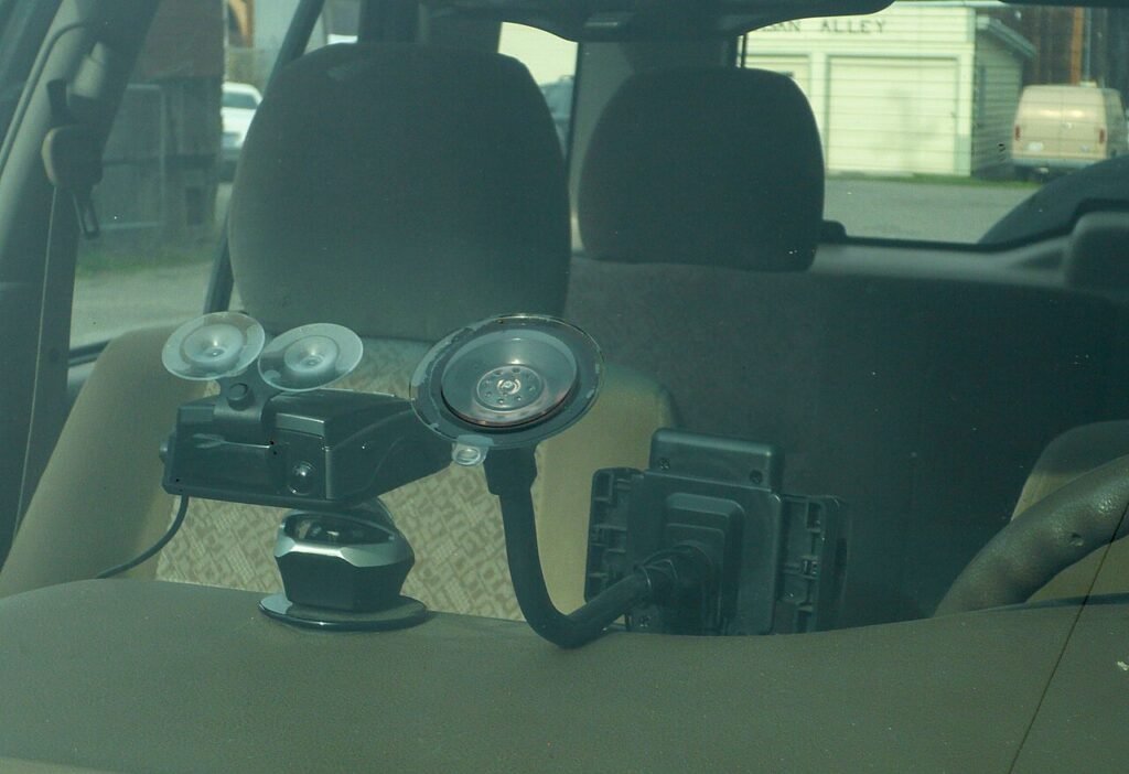 Dash camera fixed behind a windscreen, filming a street through the glass