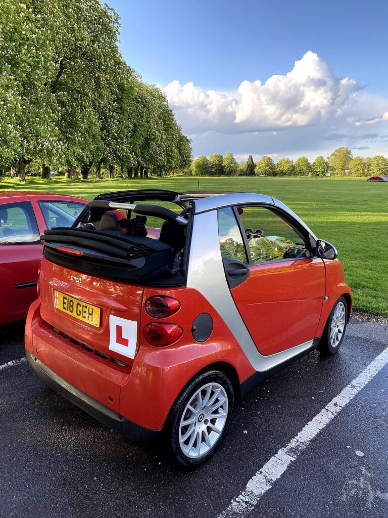 Small red hatchback with learner plates parked on a driveway