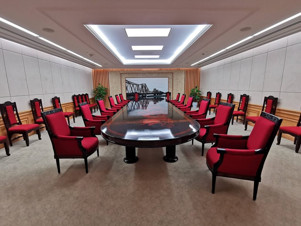 Meeting room with a long table, chairs and microphones at each place