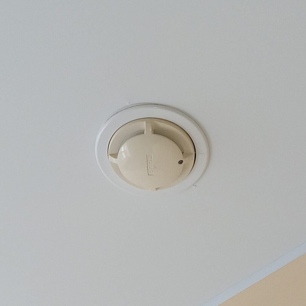 Round smoke detector fitted flush to a white ceiling